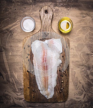 Crude Pangasius on a cutting board with butter and salt wooden rustic background top view close up