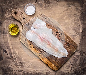 Crude Pangasius on a cutting board with butter and salt wooden rustic background top view close up