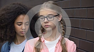 Cruel black student bullying caucasian schoolgirl eyeglasses, hitting shoulder