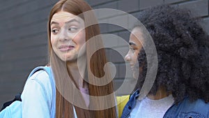 Cruel teenage girls mocking classmate passing by, malicious rumors, bullying