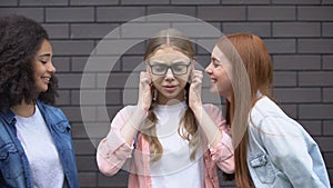 Cruel teenagers teasing female pupil eyeglasses, bullying victim covering ears