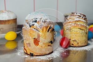 Cruffins as Easter cakes decorated with raisins, dried apricots and sugar powder on kitchen table among easter eggs