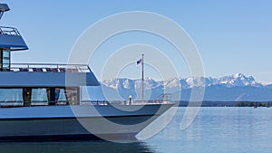 Cruise boat at Lake Starnberg with snow capped Zugspitze mountain at the horizon