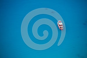 Cruise boat seen from above on clear blue water