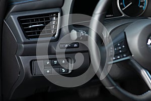 Cruise control, speed limit and volume buttons on modern car steering wheel, interior details. Buttons on the steering