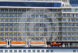 Cruise line ship side with lifeboats and balcony stateroom.