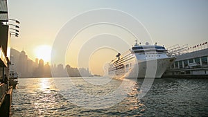 Cruise liner in Victoria harbor in the rays of sunset. View of the sea of Hong Kong and skyscrapers against the backdrop