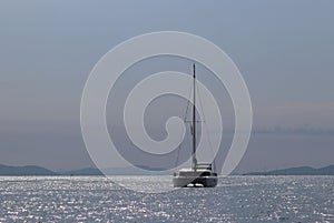 A cruise sailing catamaran lagoon 450 with a Bermuda sloop-type rig goes past the islands of the Croatian Riviera on a sunny summ