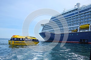 Cruise ship at anchor ourside St Peter Port, Guernsey. Large ship with blue hull and a yellow lifeboat or tenders. photo