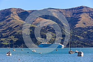 A cruise ship anchored against a mountainous background