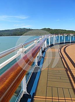 Cruise ship deck and railing with tropical island views in the background