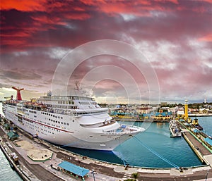 Cruise ship docked at caribbean port. Big ocean liner leaving a port at sunset