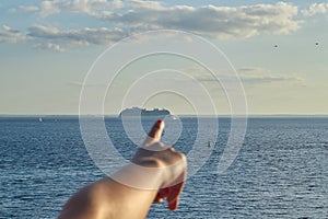 Cruise on ship hand points to cruise liner on horizon