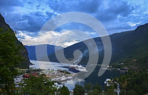 Cruise ship in the marina of famous norwegian village Flam in sea harbor with green mountains