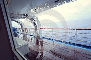 Cruise ship Open deck with Rescue Lifeboats and life buoy through the Window in raindrops