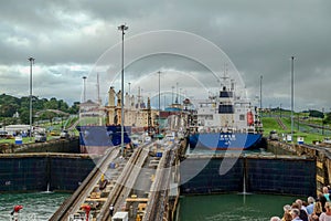 A cruise ship with the passengers on the bow watching ships going through the Panama Canal