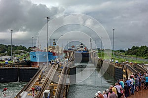 A cruise ship with the passengers on the bow watching ships going through the Panama Canal