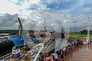 A cruise ship with the passengers on the bow watching ships going through the Panama Canal