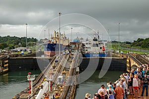 A cruise ship with the passengers on the bow watching a the water being raise  on the first lock in the Panama Canal