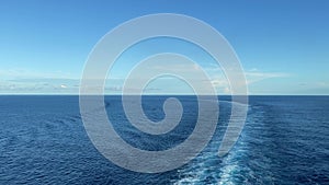 A cruise ship wake in the Atlantic Ocean on a sunny day with dark blue water