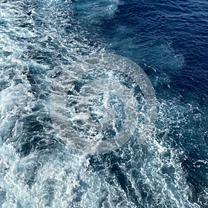 Cruise ship wake on a beautiful sunny day with white clouds and blue seas