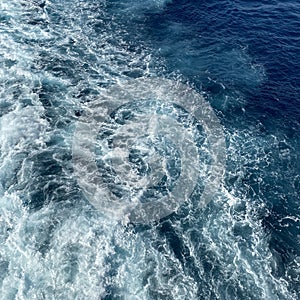 Cruise ship wake on a beautiful sunny day with white clouds and blue seas