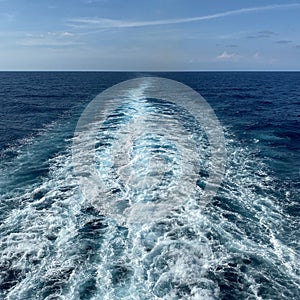 Cruise ship wake on a beautiful sunny day with white clouds and blue seas