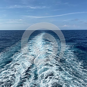 Cruise ship wake on a beautiful sunny day with white clouds and blue seas