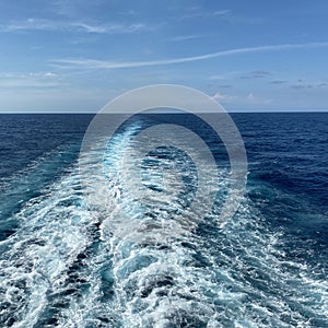 Cruise ship wake on a beautiful sunny day with white clouds and blue seas
