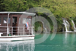 Cruise ship with a waterfall in the background in the Plitvice Lakes National Park