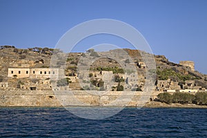 Cruise to the island of Spinalonga. Small boat on the blue lagoon. Spinalonga fortress on the island of Crete, Greece.