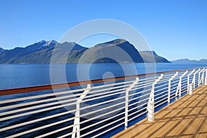 Cruise towards Geiranger fjord on a beautiful day with views of the Norweigan mountains from the open promenade deck of the ship.