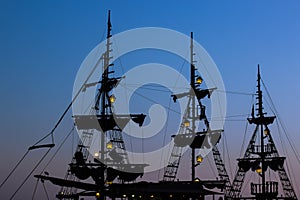 Cruise vacation medieval vintage ship mast dark silhouette shape on twilight blue evening sky background after sunset with