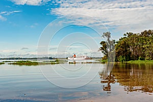 Cruiser, Cruise Liner on River Amazon with typical riparian vegetation on shore.