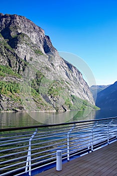 Cruising Geiranger fjord on a beautiful day with views of the Norwegian mountains from the open deck of the ship, Norway.
