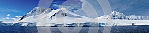 Cruising through the Neumayer channel with snow covered mountains in Antarctica.