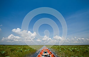 Cruising wooden boat in the lake with cloudy blue sky background