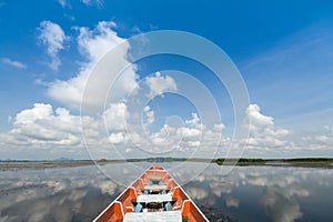 Cruising wooden boat in the lake with cloudy blue sky background