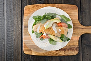 Crumbed fish fillet burrito with avocado and tomato