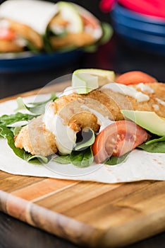 Crumbed fish fillet burrito with avocado and tomato