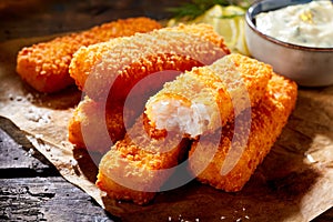 Crumbed fish fingers in sticks with tartare sauce photo