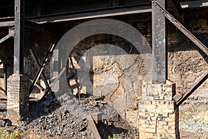 Crumbling concrete and brick wall, outriggers of steel I-beams, rubble beneath