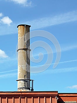 Crumbling concrete smokestack against a blue sky