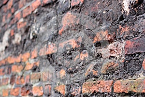A crumbling old red brick wall background texture in shallow depth of field. stone wall selective focus