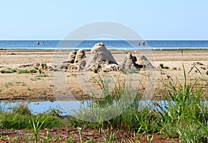 Crumbling sand castles on the beach, green grass