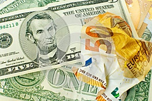 The crumpled 50 euro bill is on on US dollars. Lincoln with a 5 dollar bill grins over crumpled 50 euros. Currency exchange