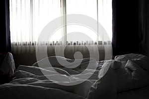 Crumpled bed and white blanket in the hotel in the morning