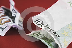 crumpled bill of one hundred euros and dollars lying on a red background