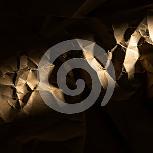 Crumpled brown paper with dramatic lighting creates contrasting shadows and