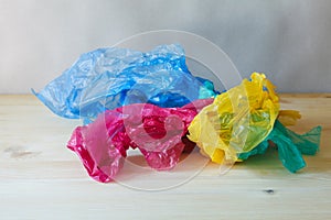 Crumpled colorful plastic bags and wraps on wooden table